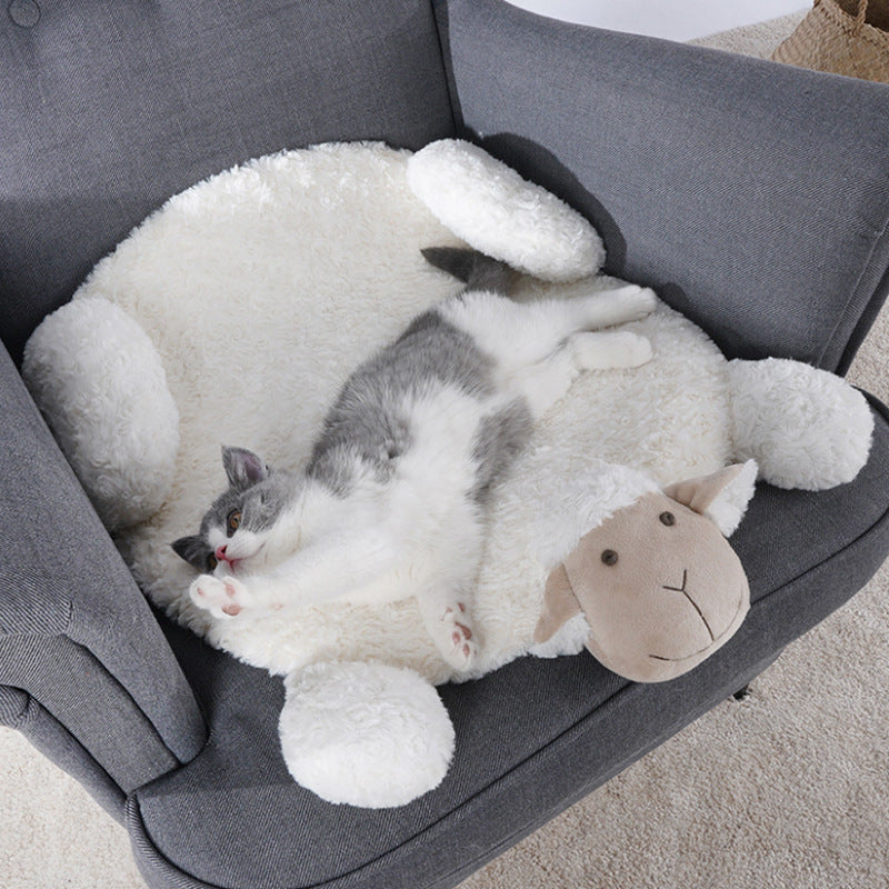A grey and white cat comfortably stretched out on a fluffy, lamb-shaped pet bed placed on a grey armchair.
