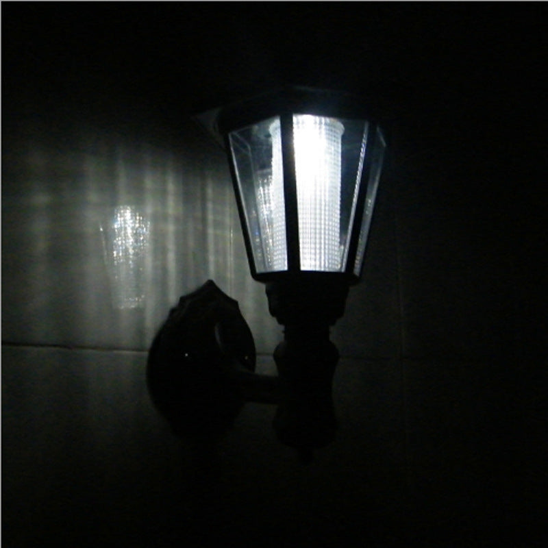 Fence-mounted solar light glowing at night, perfect for garden and pathway illumination.








